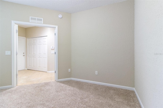 carpeted spare room featuring a textured ceiling