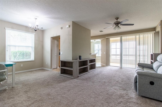 living room with a textured ceiling, light colored carpet, and ceiling fan with notable chandelier