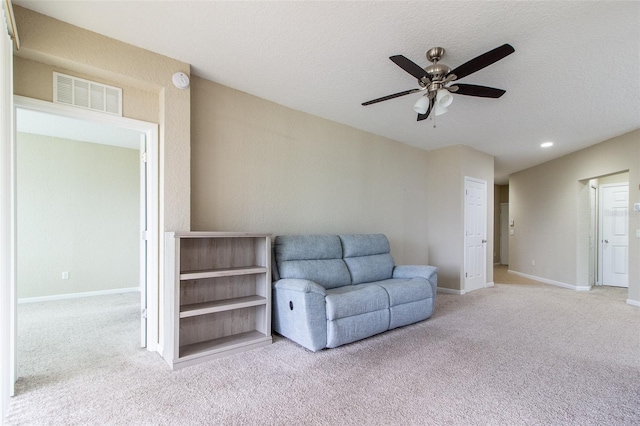 sitting room with a textured ceiling, ceiling fan, and light carpet