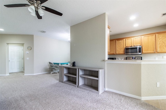 kitchen with light carpet, stove, a textured ceiling, and ceiling fan