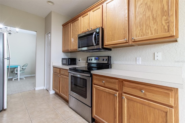 kitchen with light tile patterned floors, a textured ceiling, and appliances with stainless steel finishes