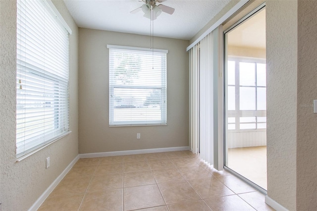 unfurnished room featuring ceiling fan, light tile patterned floors, and a textured ceiling