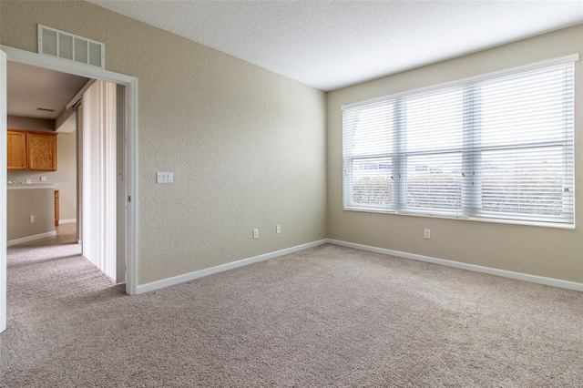 carpeted empty room featuring a textured ceiling