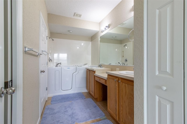 bathroom with tile patterned flooring, vanity, and a textured ceiling