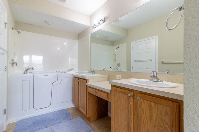 bathroom with tile patterned floors, a washtub, a textured ceiling, and vanity