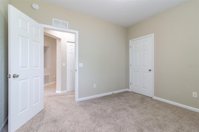 unfurnished bedroom with a textured ceiling and light carpet