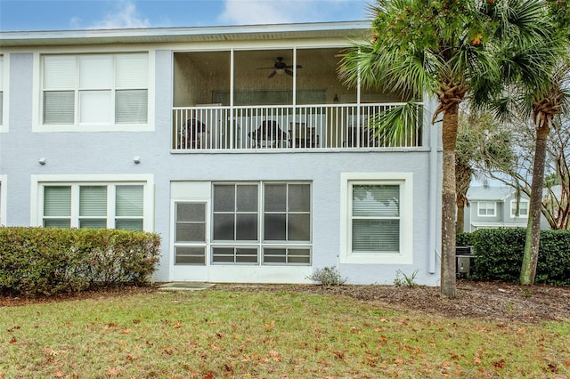 back of house featuring a lawn, ceiling fan, and a sunroom