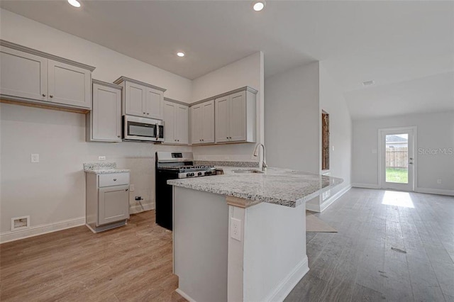 kitchen featuring light stone countertops, sink, stainless steel appliances, light hardwood / wood-style floors, and gray cabinets