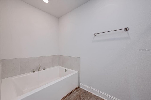 bathroom with a washtub and hardwood / wood-style flooring