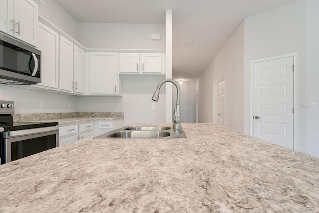 kitchen featuring white cabinetry, stainless steel appliances, light stone countertops, and sink