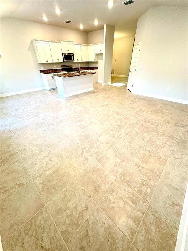 3127 NE 45th Ave, Ocala, FL 34470 - kitchen featuring stainless steel microwave, open floor plan, white cabinets, and dark countertops