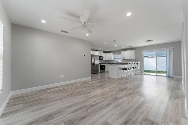 unfurnished living room with light hardwood / wood-style flooring and ceiling fan