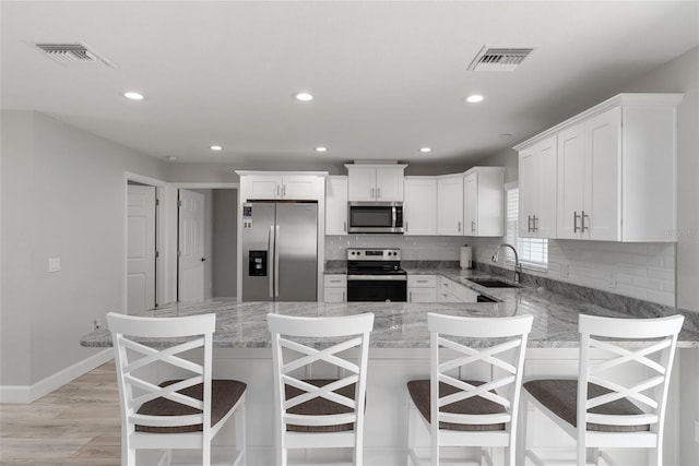 kitchen featuring appliances with stainless steel finishes, white cabinets, sink, and a kitchen breakfast bar