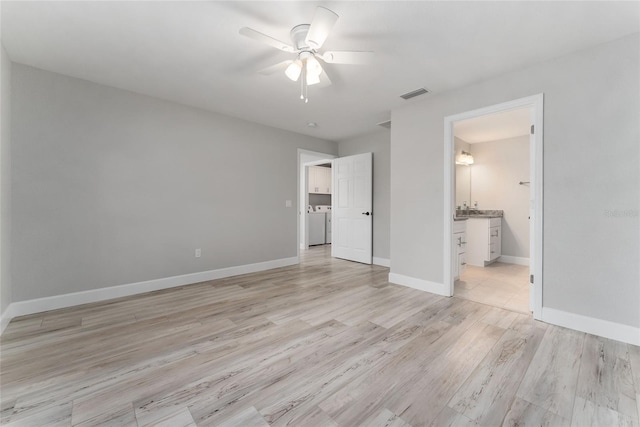 unfurnished bedroom with connected bathroom, light hardwood / wood-style flooring, washer / clothes dryer, and ceiling fan