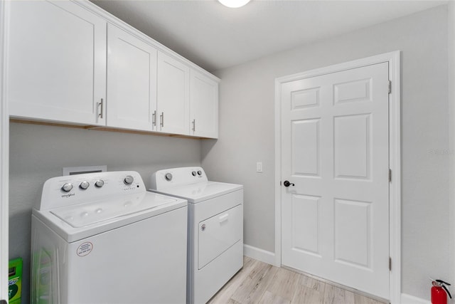 laundry room with light hardwood / wood-style floors, cabinets, and washing machine and clothes dryer