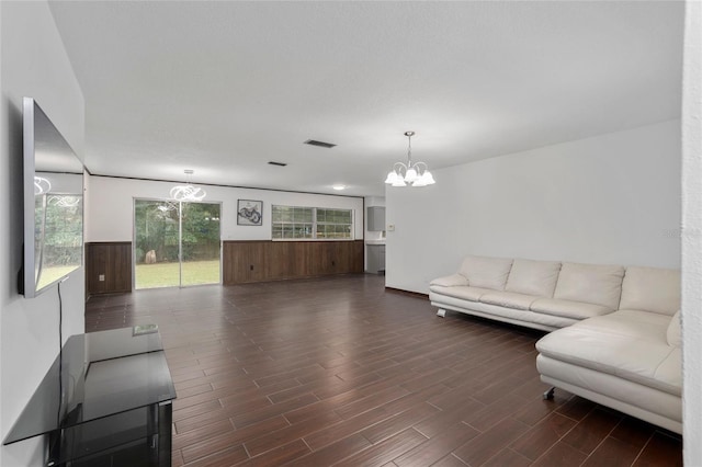 living room with a wealth of natural light, an inviting chandelier, and dark hardwood / wood-style flooring