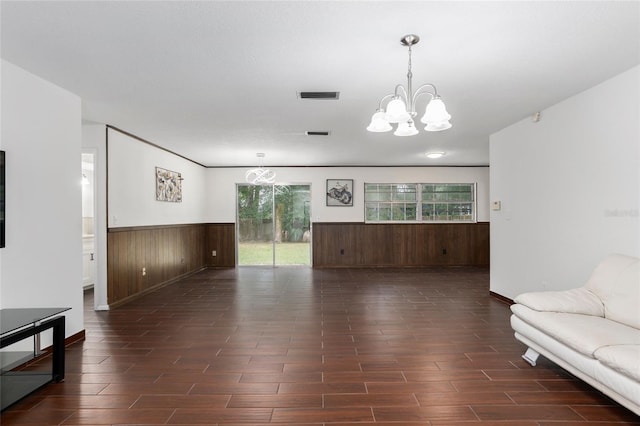 living room featuring wood walls, a chandelier, and dark wood-type flooring