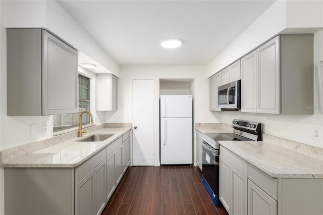 kitchen featuring sink, dark hardwood / wood-style flooring, stainless steel appliances, gray cabinets, and light stone counters