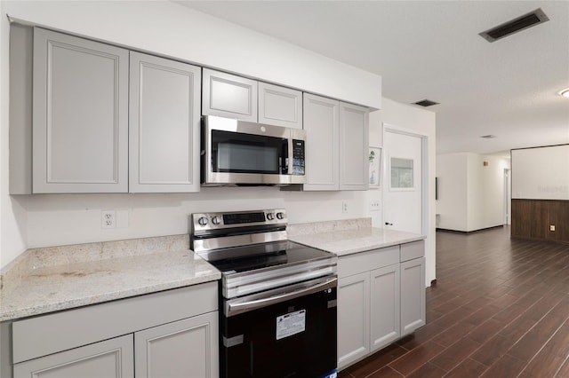 kitchen featuring dark wood-type flooring, stainless steel appliances, light stone countertops, and gray cabinetry