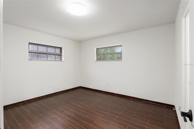 empty room with a textured ceiling and dark hardwood / wood-style floors