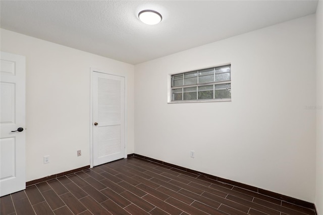 spare room featuring dark wood-type flooring and a textured ceiling