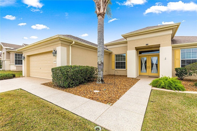 view of front of home featuring an attached garage, driveway, french doors, stucco siding, and a front lawn