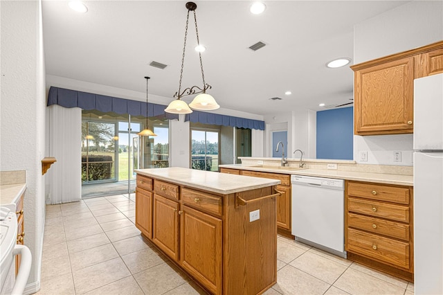 kitchen featuring white appliances, visible vents, a center island, light countertops, and a sink