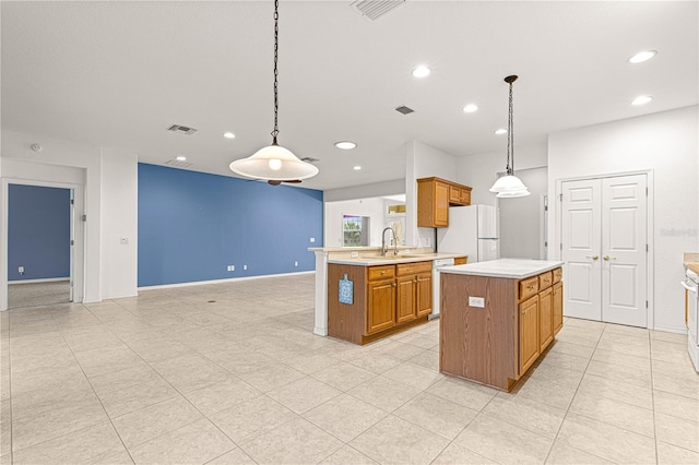 kitchen with brown cabinets, light countertops, visible vents, a sink, and white appliances