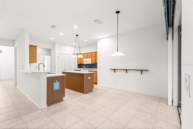 kitchen with white appliances, visible vents, a kitchen island, and backsplash