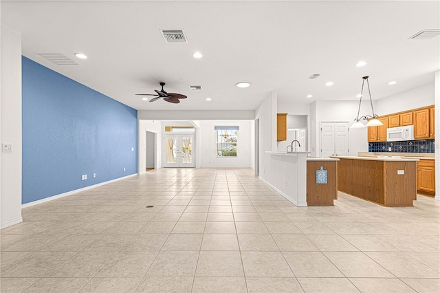 kitchen with a center island, light countertops, visible vents, white microwave, and open floor plan