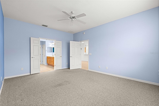 unfurnished bedroom featuring light carpet, ensuite bath, baseboards, and visible vents