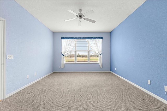 empty room featuring ceiling fan, carpet floors, a textured wall, and baseboards