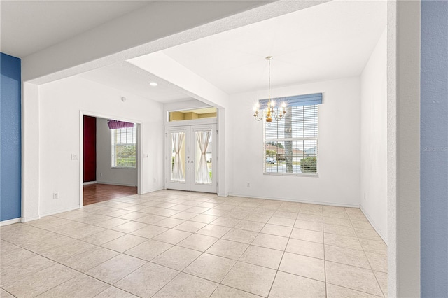 spare room featuring a chandelier, french doors, light tile patterned floors, and baseboards