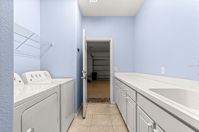 laundry area featuring light tile patterned floors, separate washer and dryer, a sink, and cabinet space