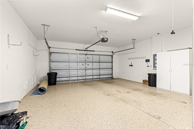 garage featuring concrete block wall and a garage door opener