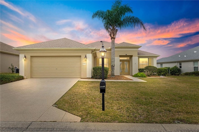 view of front of property featuring driveway, a lawn, an attached garage, and stucco siding