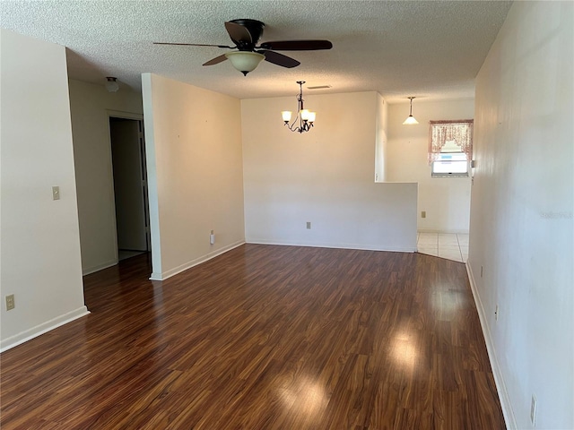 empty room with a textured ceiling, dark wood-type flooring, and ceiling fan with notable chandelier