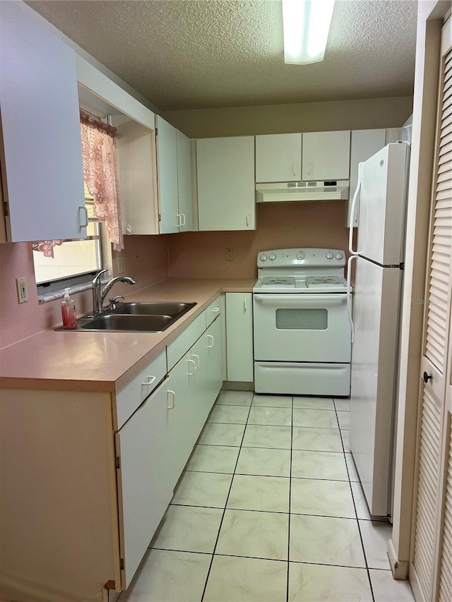 kitchen with a textured ceiling, sink, light tile patterned floors, and white appliances