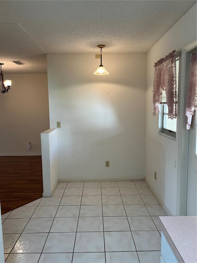 unfurnished dining area featuring light hardwood / wood-style flooring and a textured ceiling