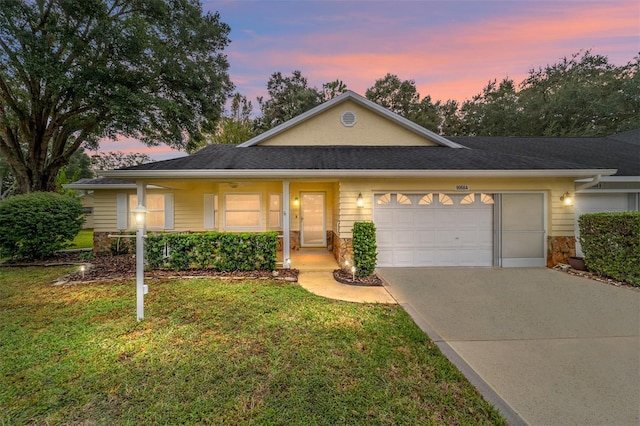 ranch-style house featuring a lawn, covered porch, and a garage