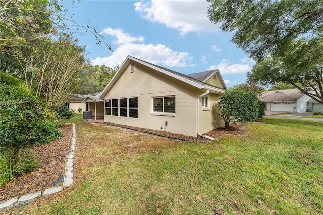 view of side of property with a garage, a lawn, and central AC