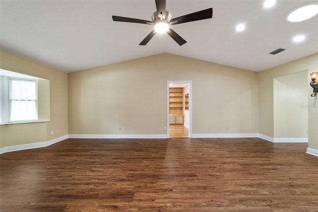 spare room featuring dark wood-type flooring, vaulted ceiling, and ceiling fan