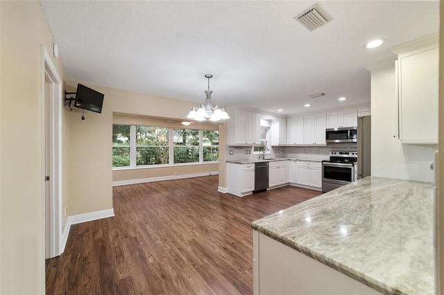 kitchen with white cabinetry, light stone counters, appliances with stainless steel finishes, dark hardwood / wood-style floors, and hanging light fixtures