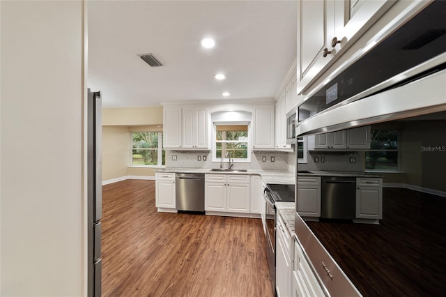 kitchen featuring white cabinetry, sink, appliances with stainless steel finishes, dark hardwood / wood-style floors, and backsplash