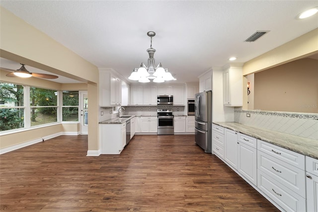 kitchen with white cabinetry, appliances with stainless steel finishes, hanging light fixtures, and light stone counters