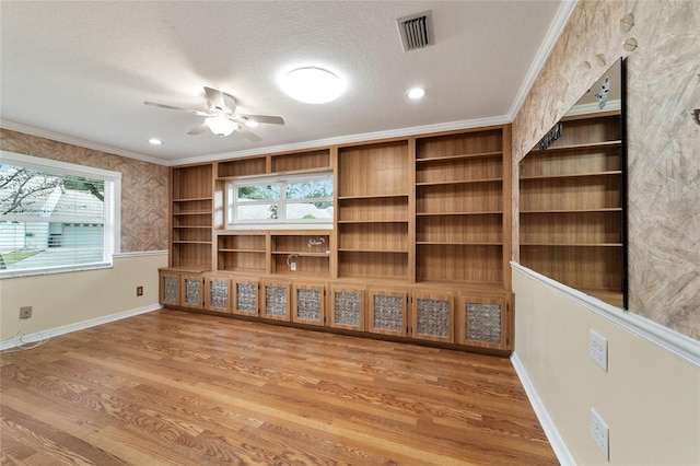 unfurnished living room featuring ceiling fan, a textured ceiling, hardwood / wood-style flooring, and ornamental molding