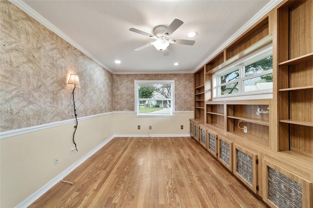 interior space with light wood-type flooring, a textured ceiling, crown molding, and ceiling fan