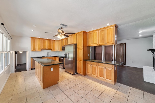 kitchen featuring a kitchen island, sink, appliances with stainless steel finishes, light hardwood / wood-style floors, and ceiling fan