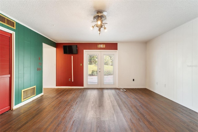 empty room featuring wood walls, ornamental molding, a textured ceiling, and dark hardwood / wood-style flooring