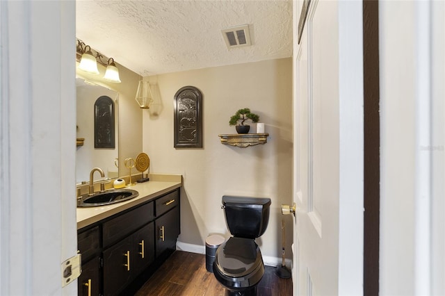 bathroom with vanity, a textured ceiling, toilet, and wood-type flooring